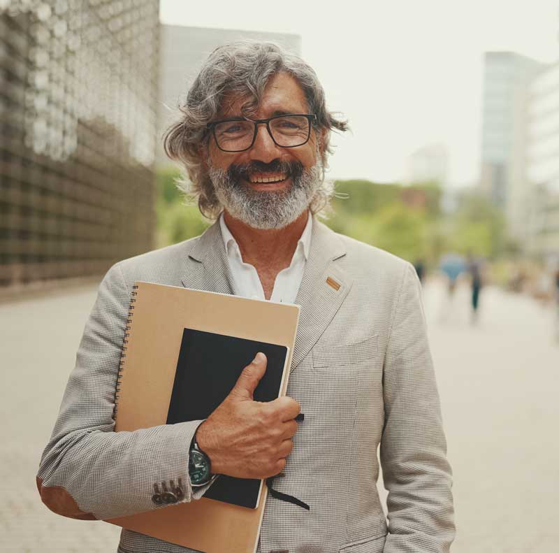 un homme cadre demandant une retraite à un consultant retraite à paris . Il à 55 ans barbu en veste beige debout derriere la défense